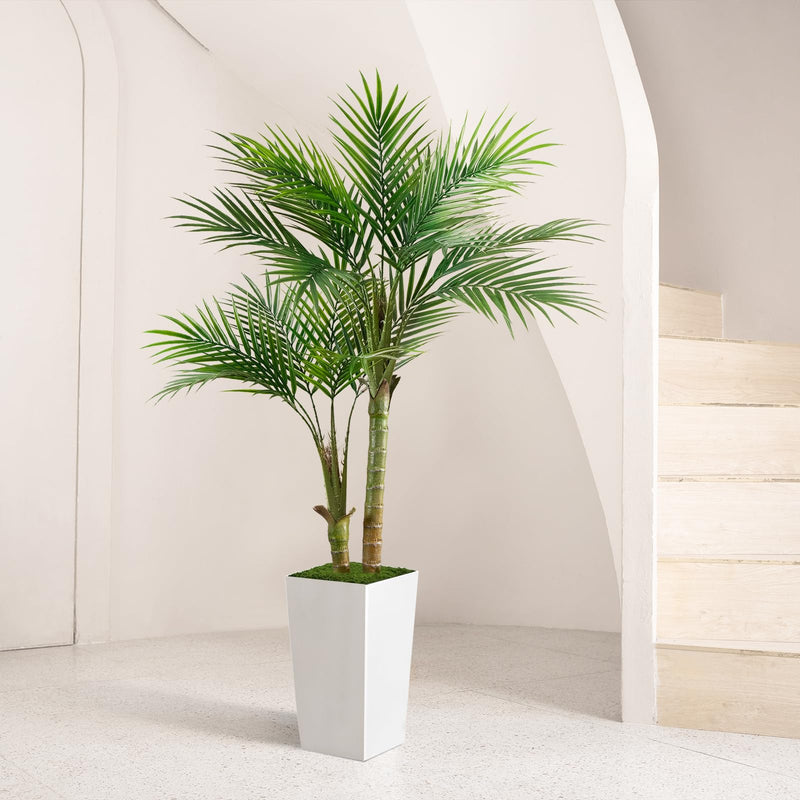 Artificial palm tree with realistic green foliage and multiple natural-look stems in a white planter, styled in a bright neutral modern interior.